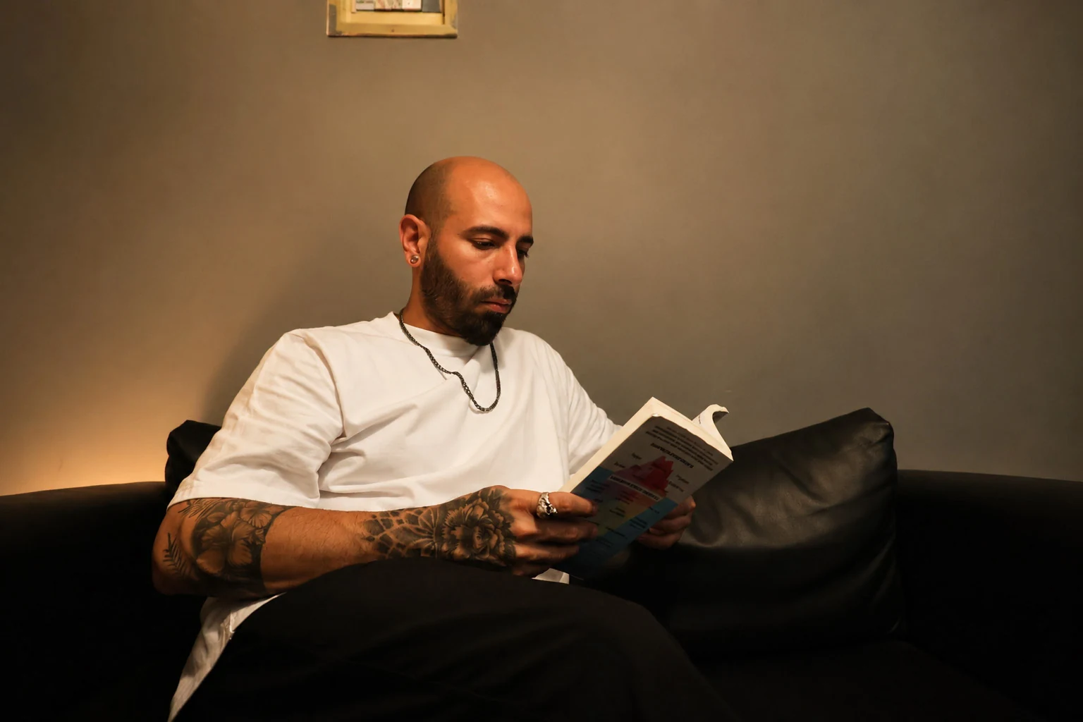 Jad Ballout reading on a black sofa